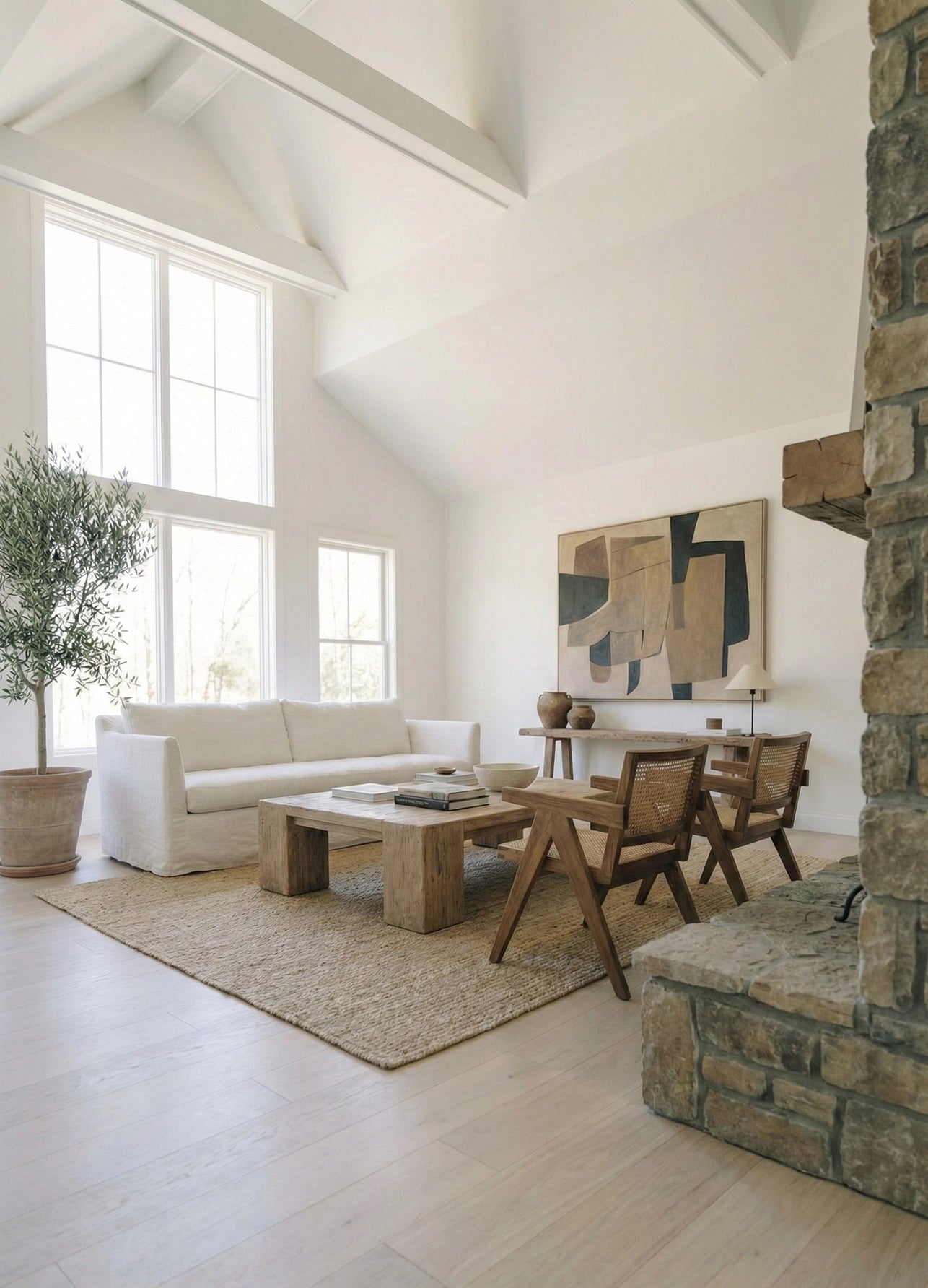 Modern living room with white sofa, wooden coffee table, and abstract art on a white wall.