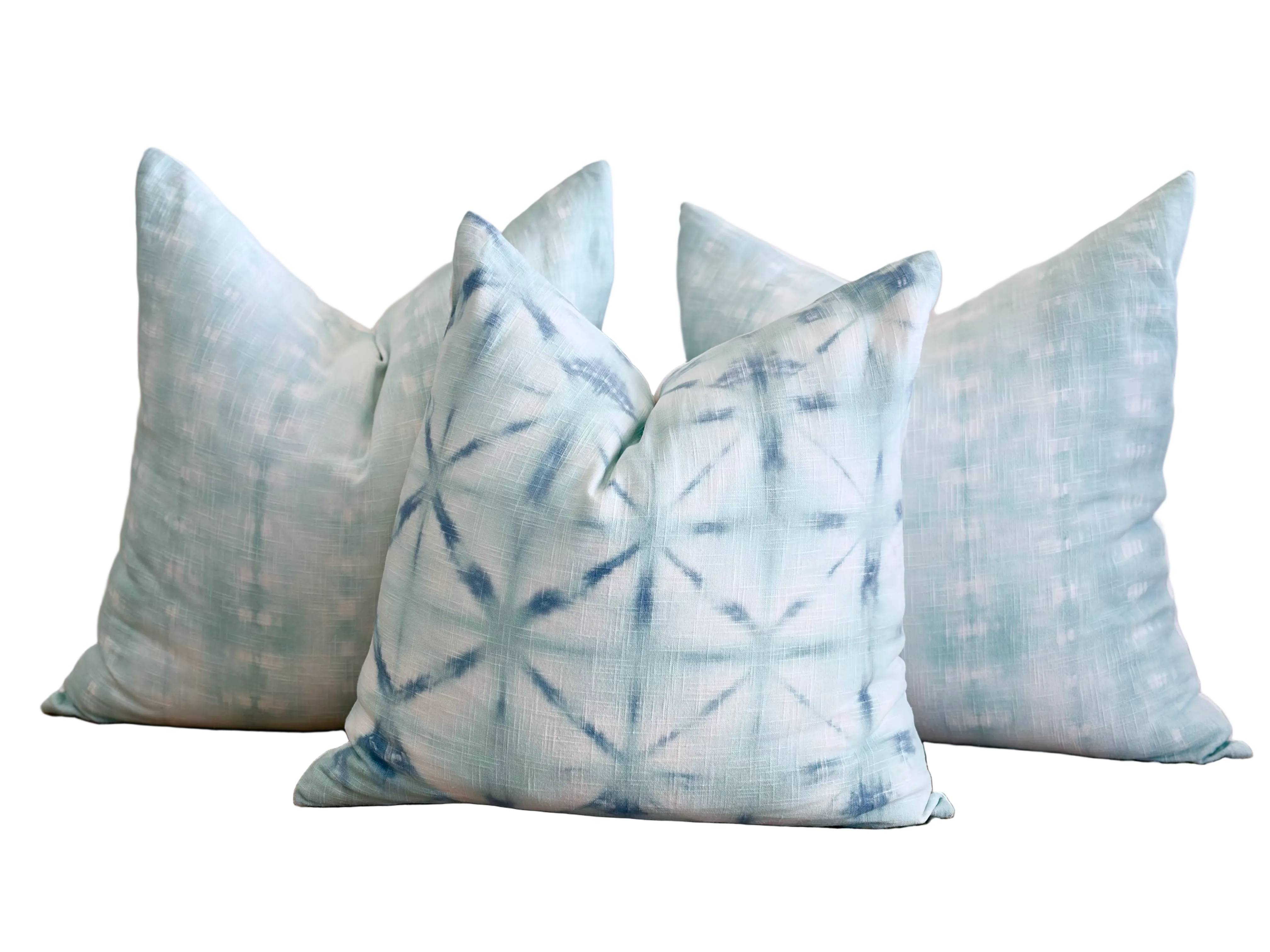 Three decorative throw pillows in a light blue and white tie-dye style